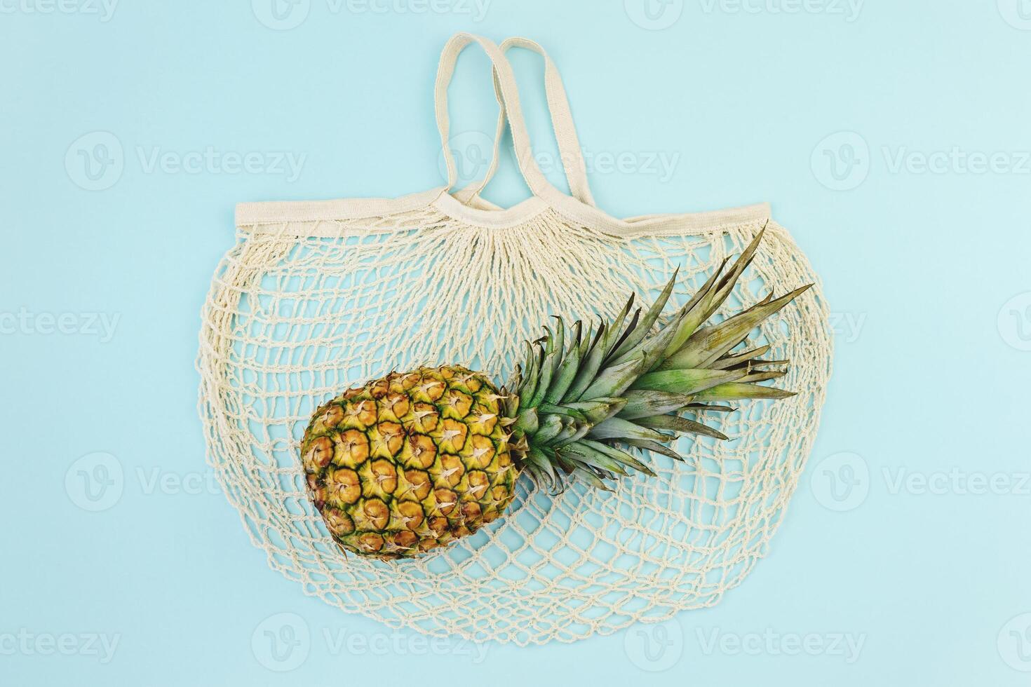Ripe Pineapple over cotton mesh bag, top view photo