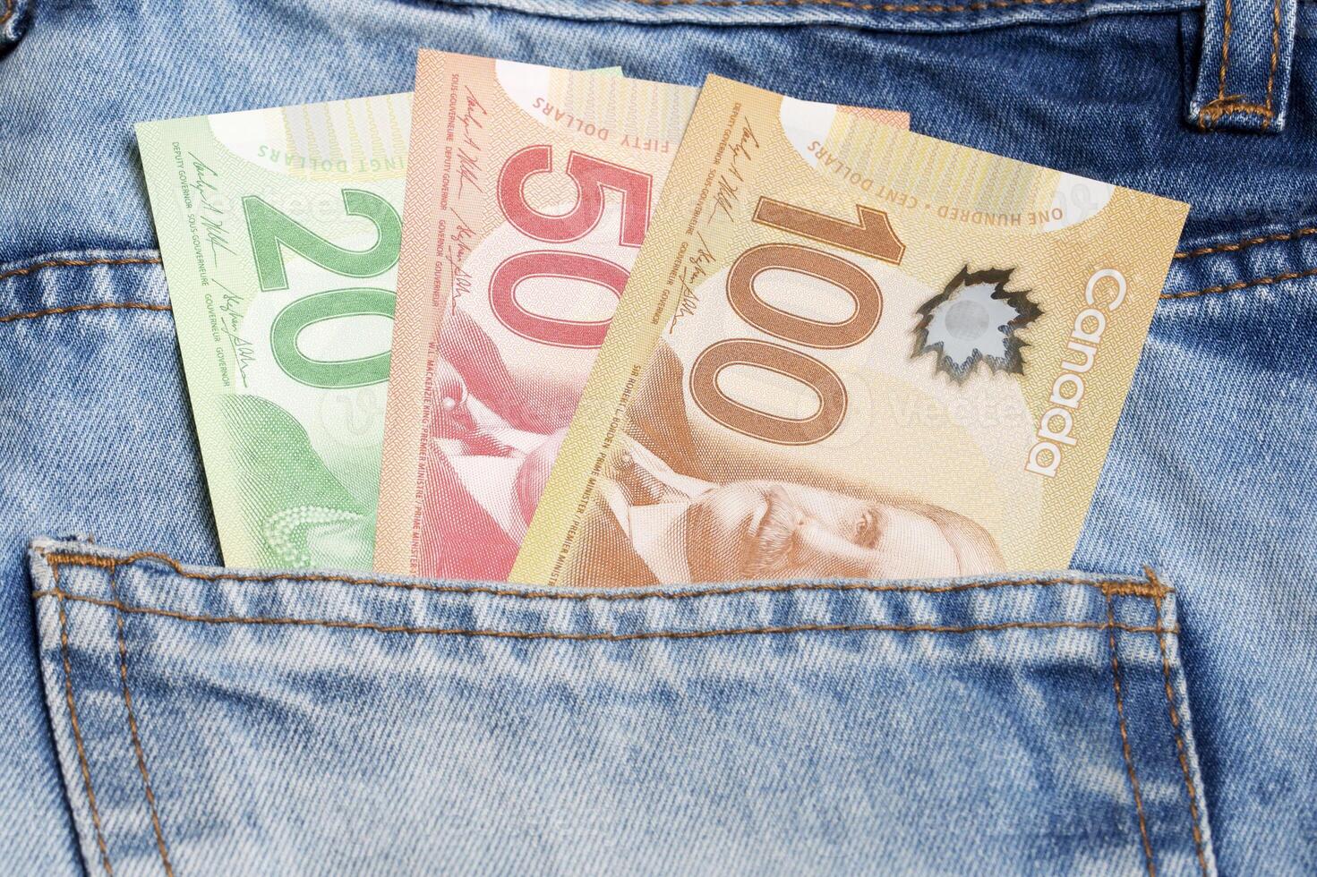 Canadian dollar in the pocket of blue jeans photo