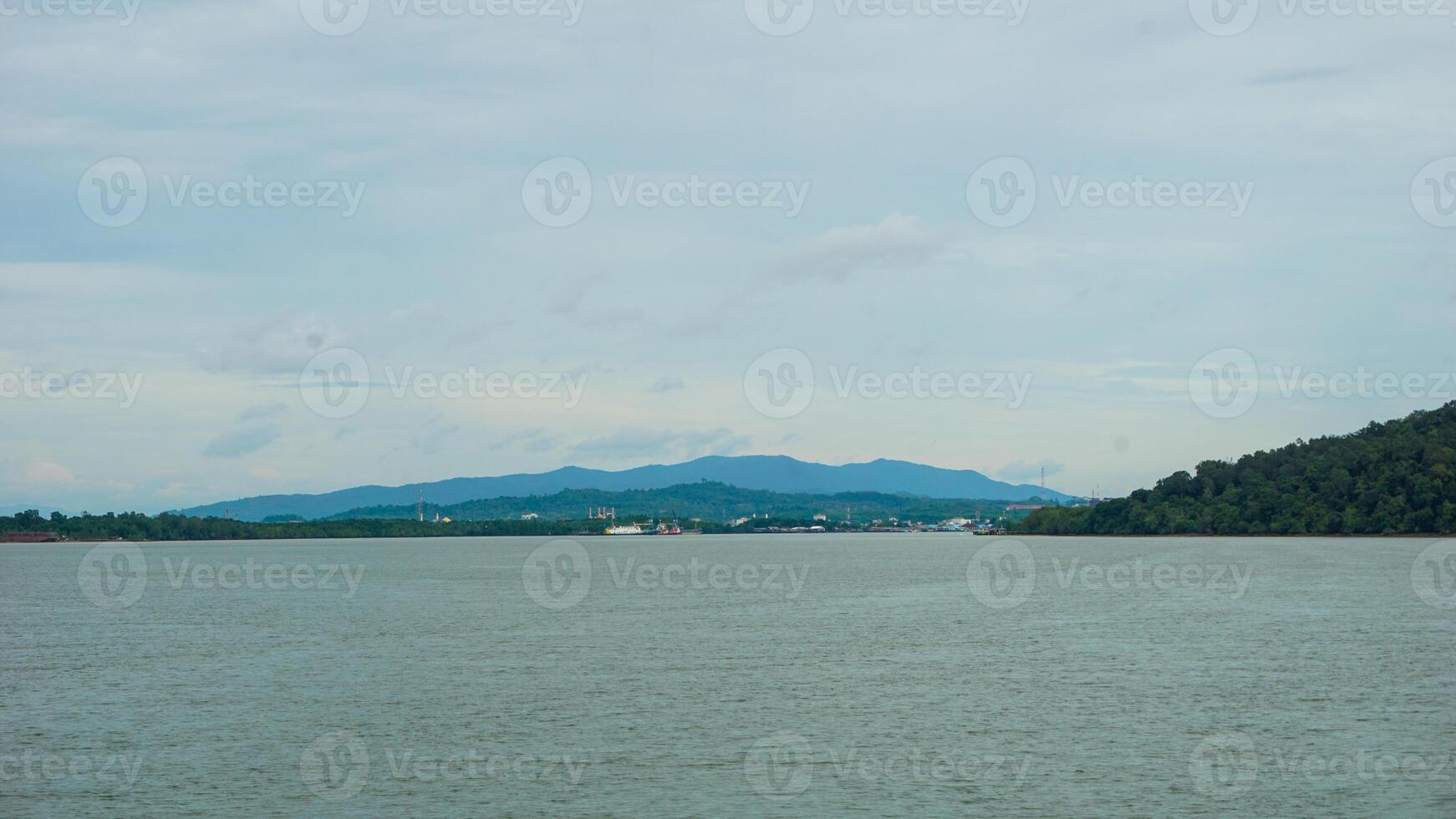 Peaceful River Landscape With Distant Hills and Lush Greenery Under Cloudy Sky photo