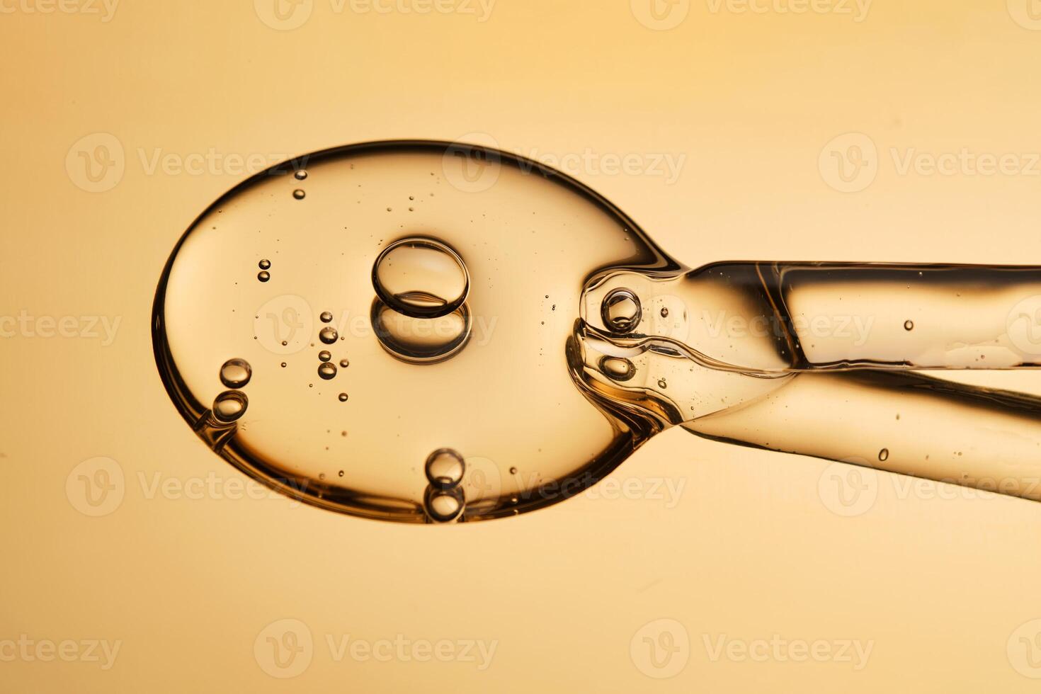 A beautiful drop of gel-like cosmetic serum with bubbles on a golden background. photo