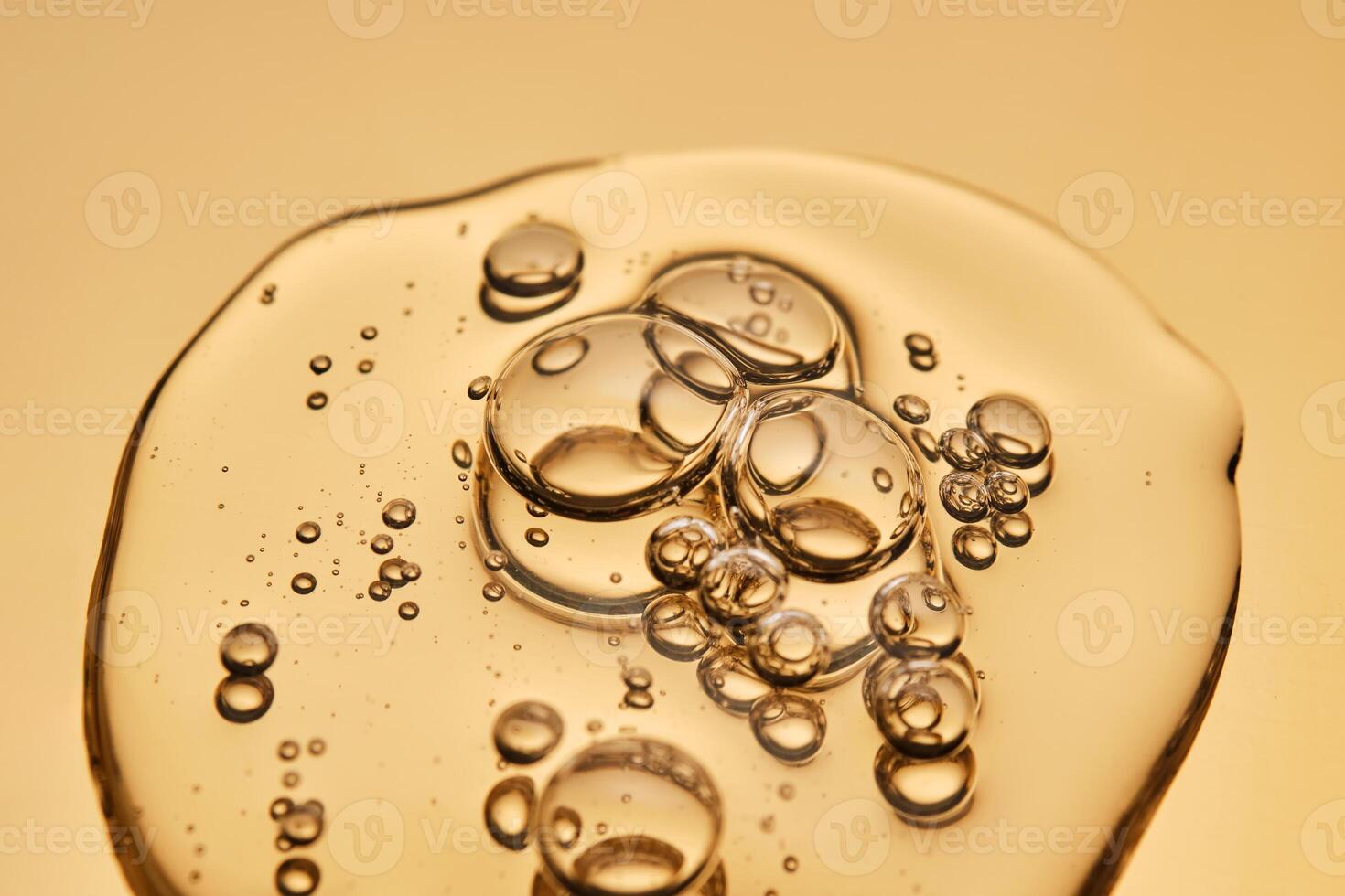 A beautiful drop of gel-like cosmetic serum with bubbles on a golden background. photo