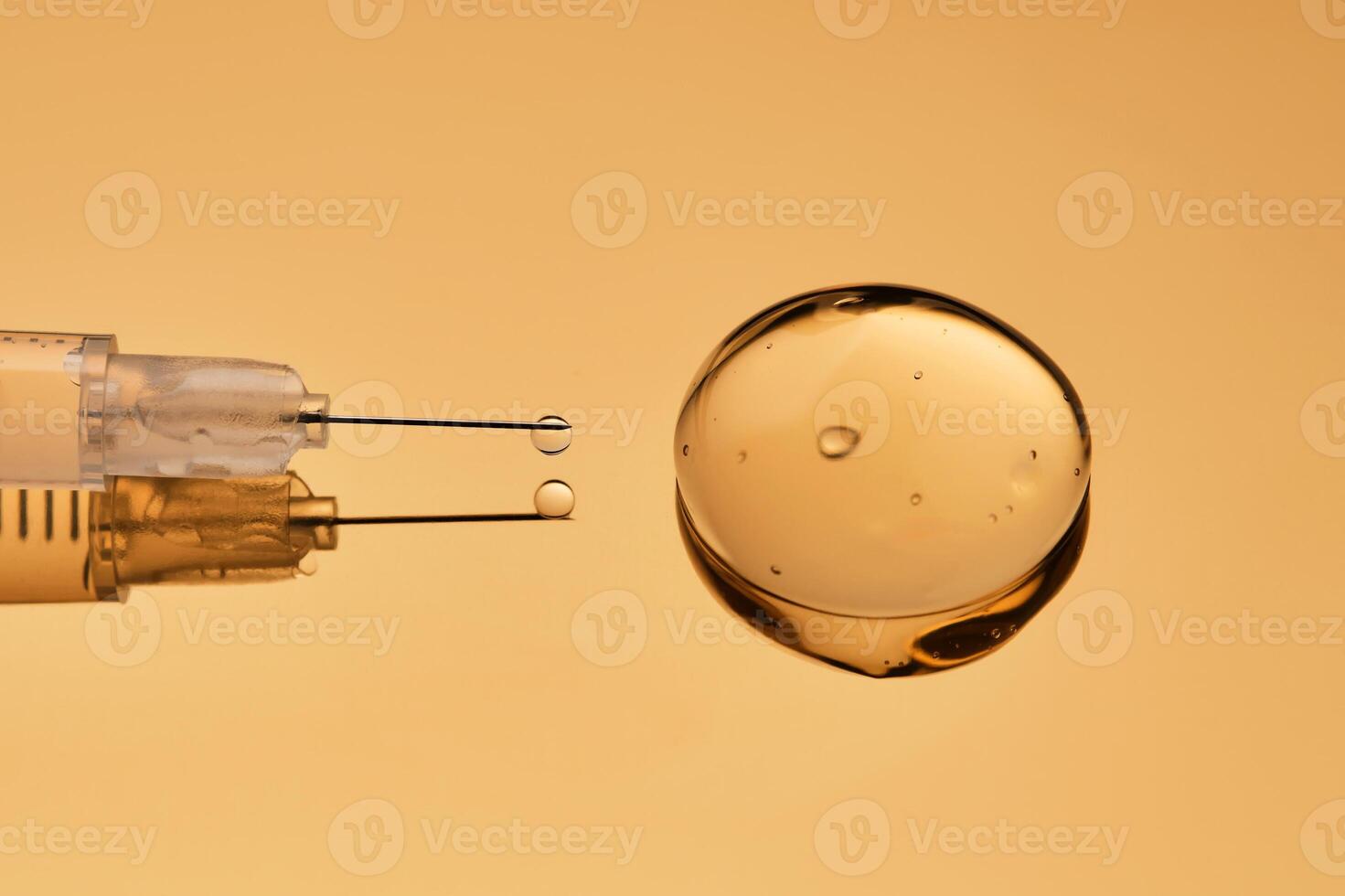 A syringe with a drop of a medical drug on a golden background. photo