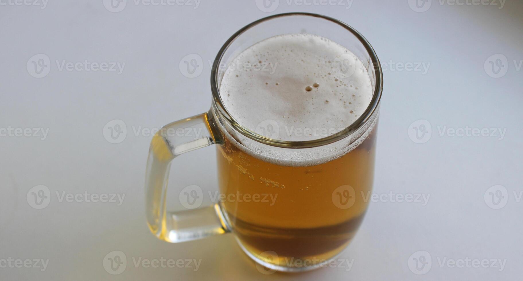 Huge beer glass with classic handle filled of craft brown beer covered with foam isolated on white photo