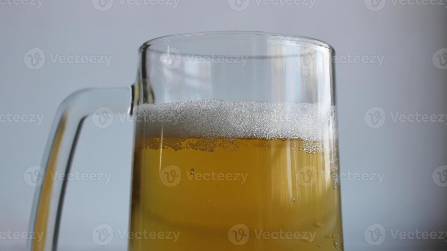 Top part of glass with handle filled of craft brown ale covered with foam closeup view photo