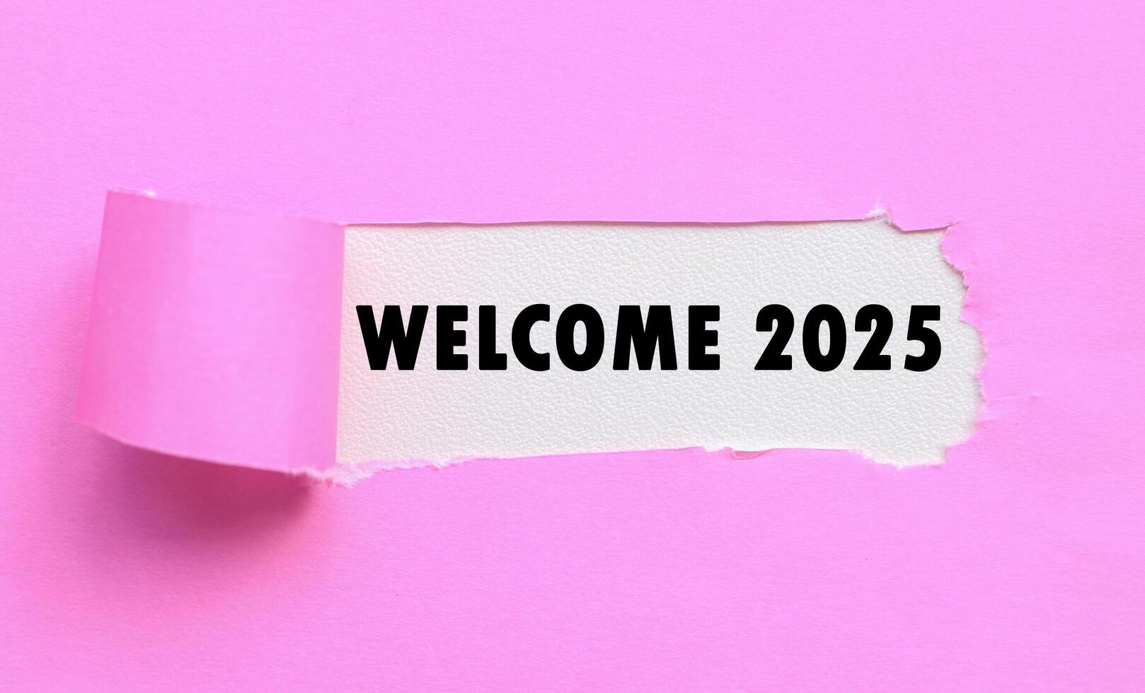 Welcome 2025 on white background and torn pink paper. New year concept with typographic welcome 2025 on paper photo