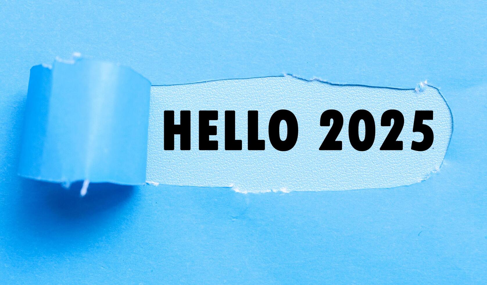 Welcome 2025 on blue background and torn blue paper. New year concept with typographic welcome 2025 on paper photo