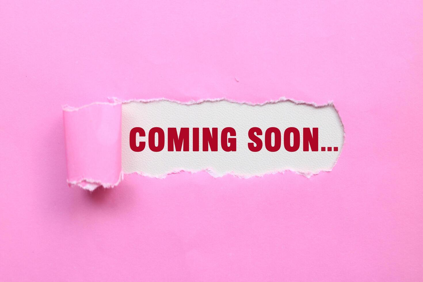 Coming soon message written on ripped torn pink paper. Text COMING SOON photo