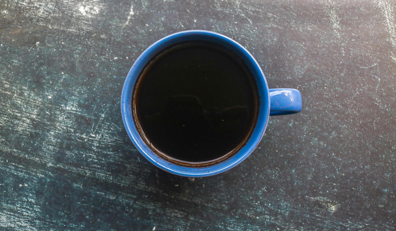 A blue cup of black coffee, top photo on a grey background with copy space