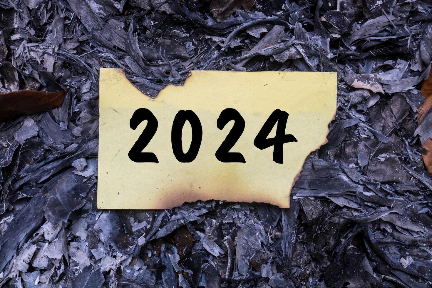 Burning paper on ashes with 2024 written on it. new life and new year 2025 concept. 2024 paper is burning, say goodbye to 2024 photo