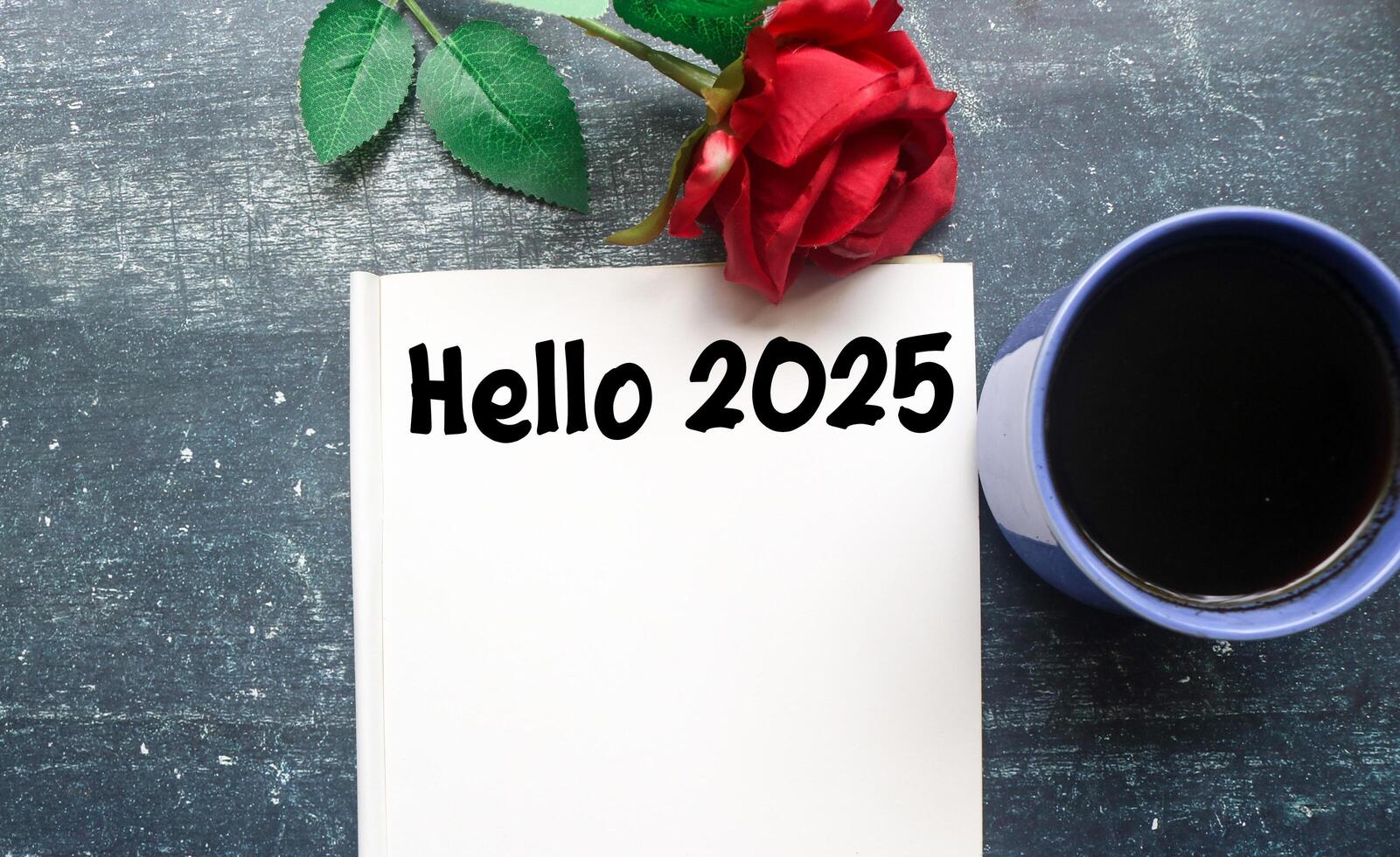A person writes Hello 2025 in a notebook surrounded by coffee and roses. Planning to do list for 2025, life goals for 2025 photo