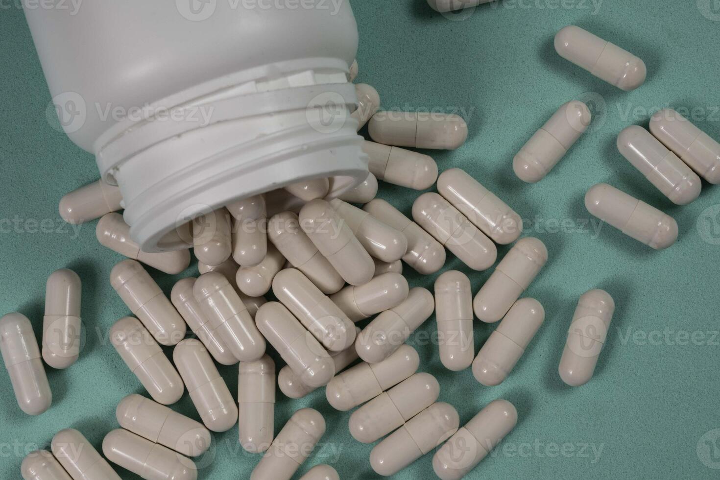 bottle of pills, some of which spilled onto a light blue photo