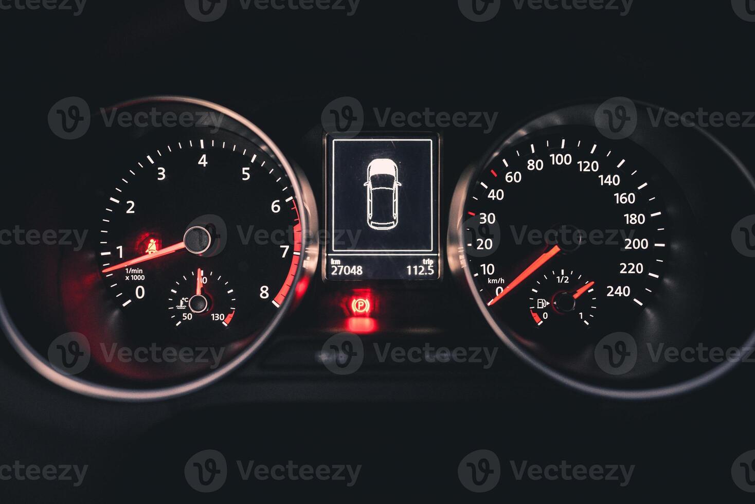 Close up of a car's dashboard at night showing the speedometer tachometer and digital display photo
