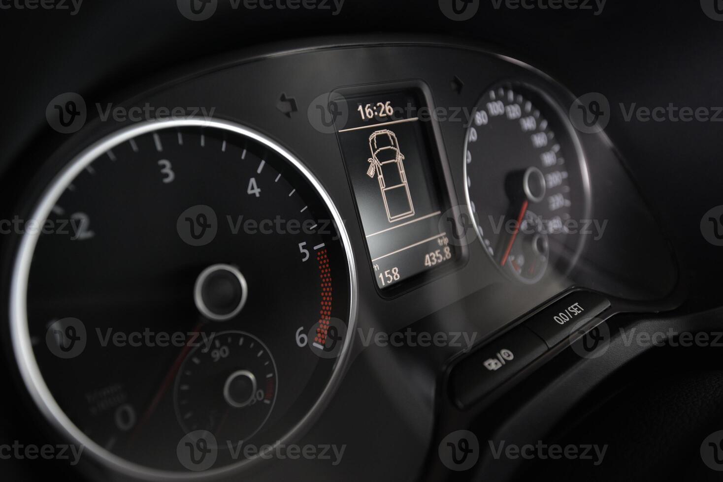 Close up of a car's dashboard showing the speedometer tachometer and digital display photo