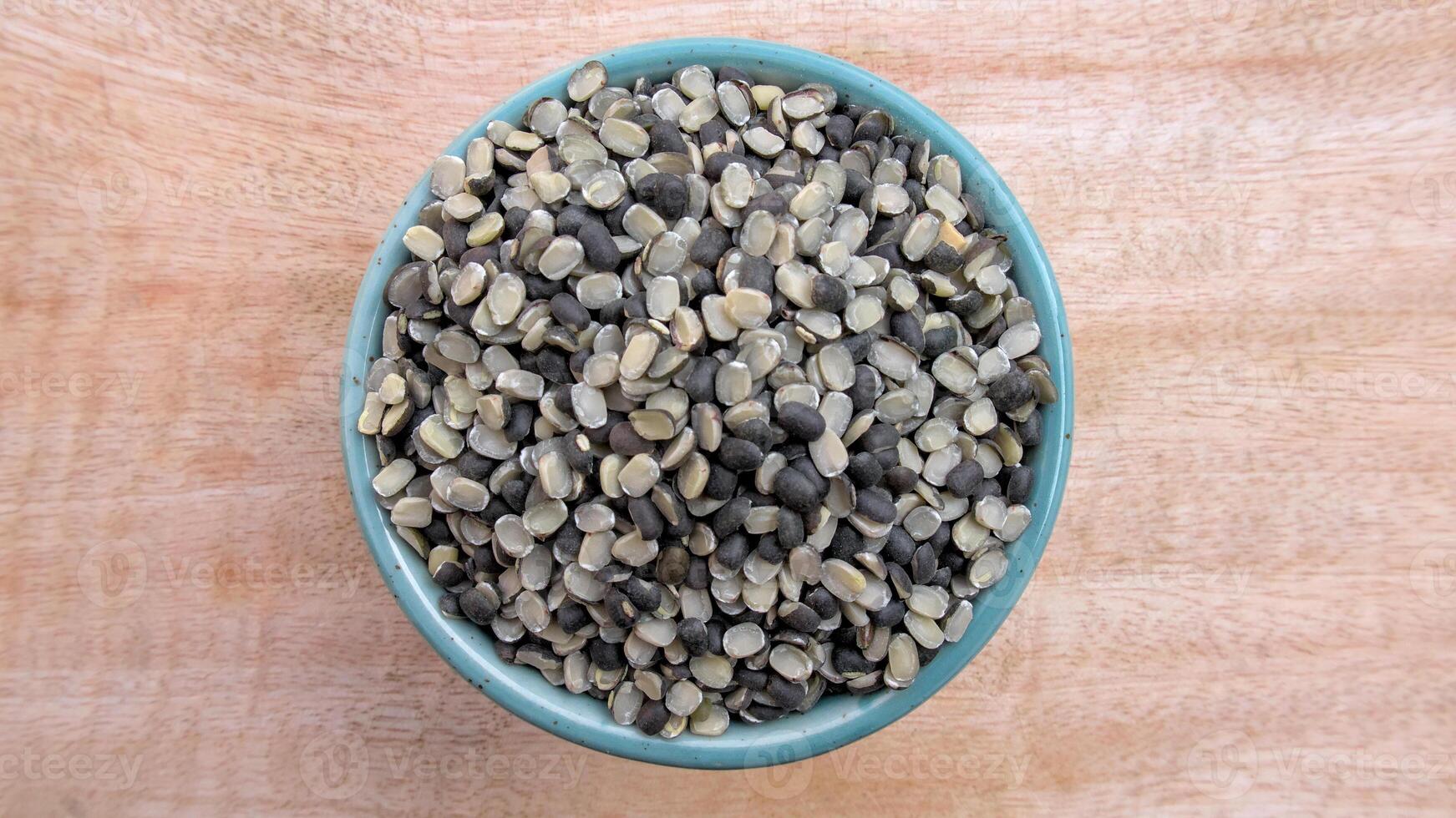 Flat Lay of Split Black Gram Black Lentil, Urad Dal, Vigna Mungo in a Bowl on Neutral Wooden Background photo
