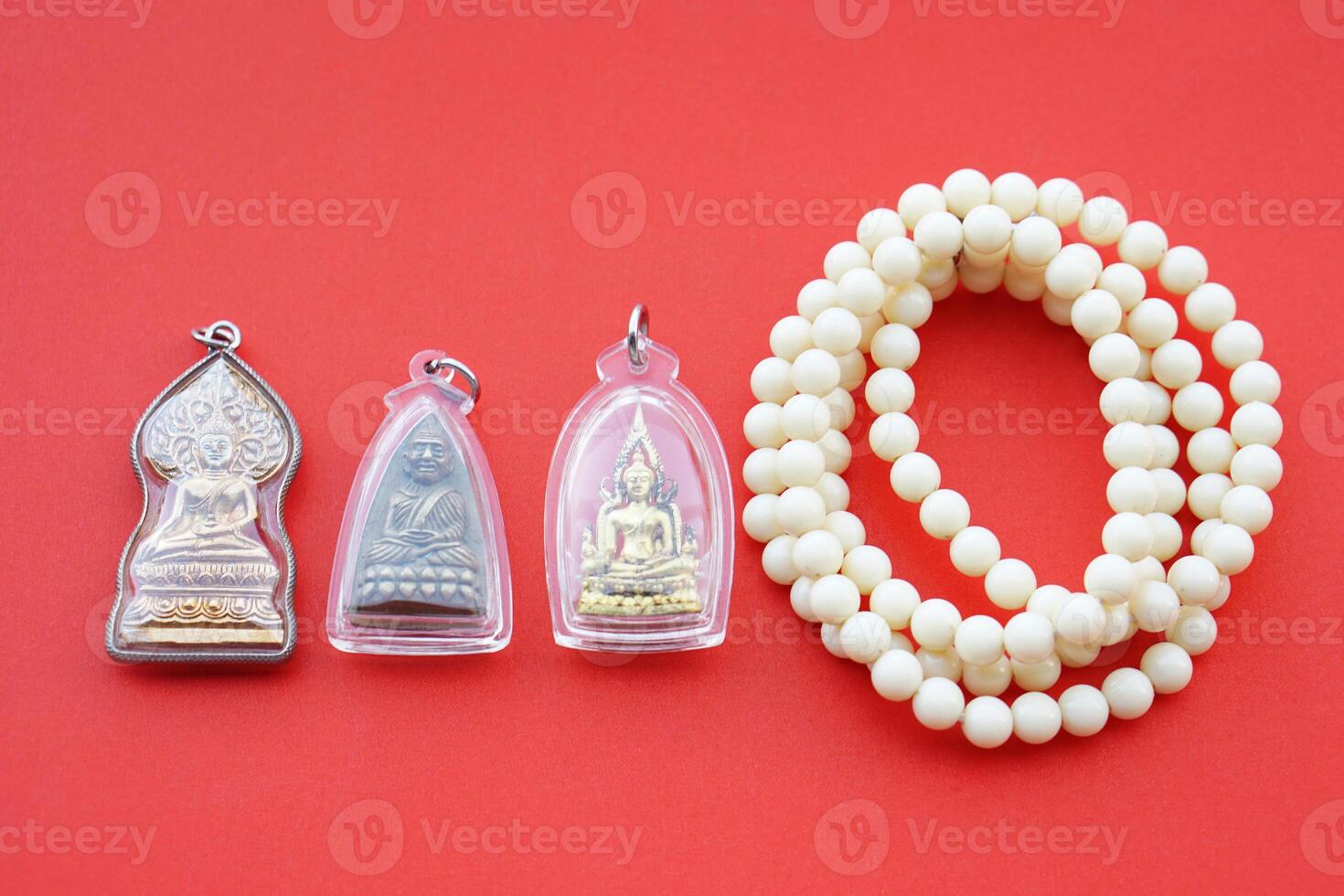 Buddha amulets and bead bracelets on red background. Concept, faith and belief of Buddhist for holy to protect from danger, bring good luck, business prosperity and wealth. Collecting amulet as hobby. photo