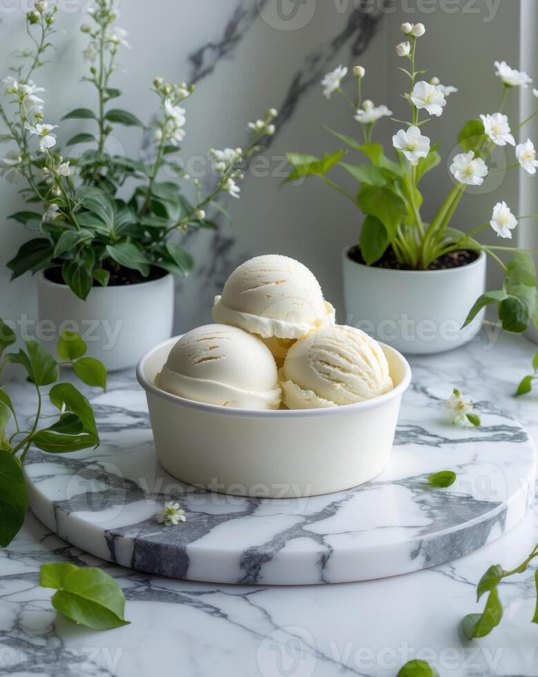 Ice cream tub with scoops set on a marble table surrounded by plants for dessert concept photo