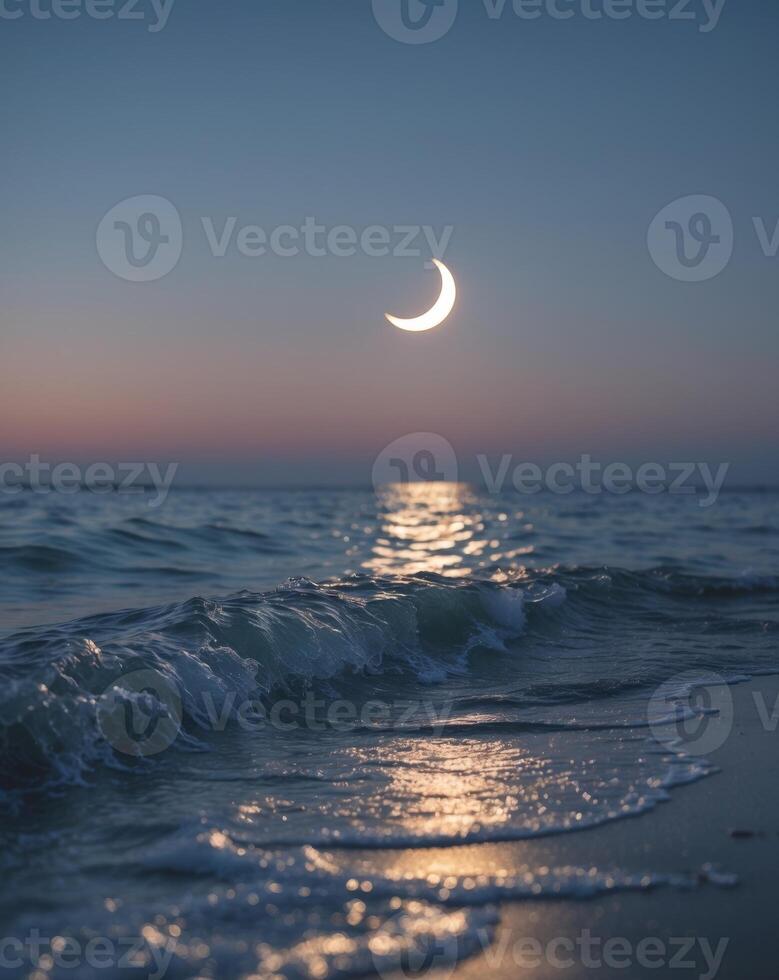 Glowing waves illuminate the shore under a crescent moon at twilight photo