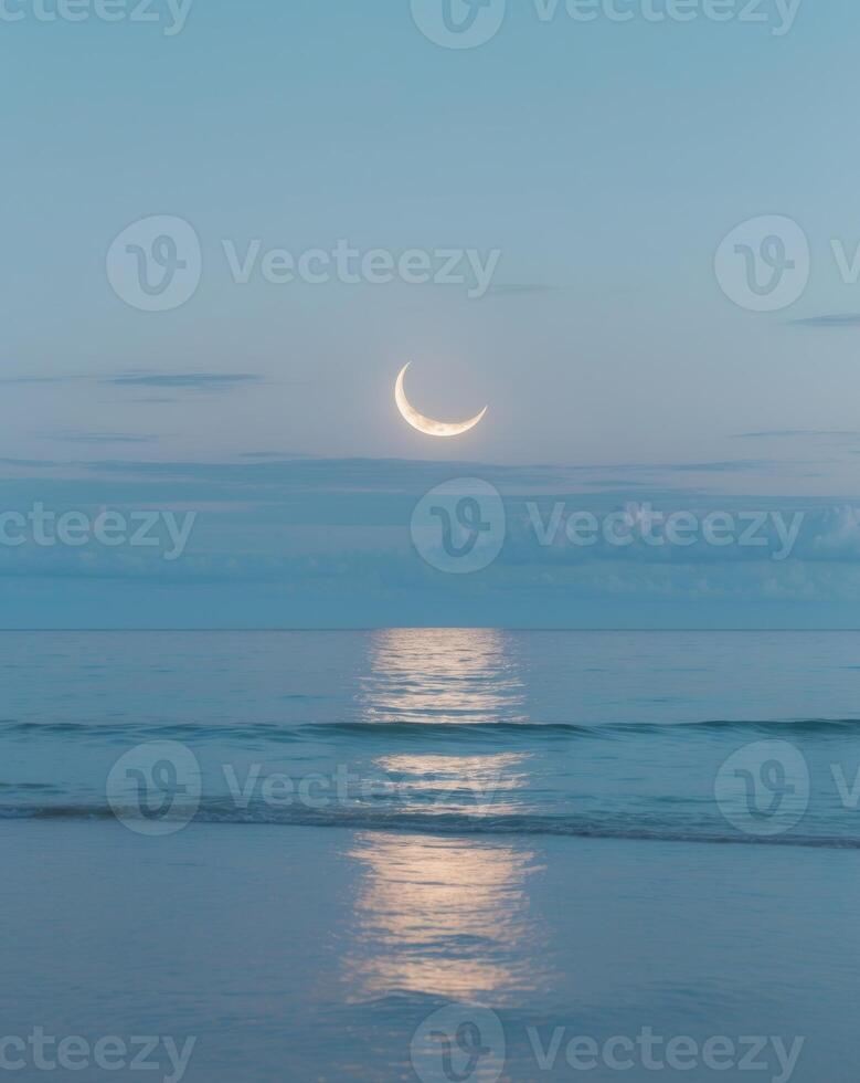 Serene cloud reflection over tranquil ocean with crescent moon at dusk photo