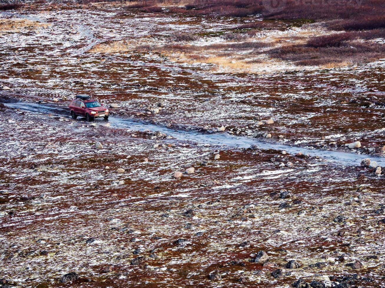 Icy slippery Arctic road through the tundra. Drop-off of tourists by car. photo