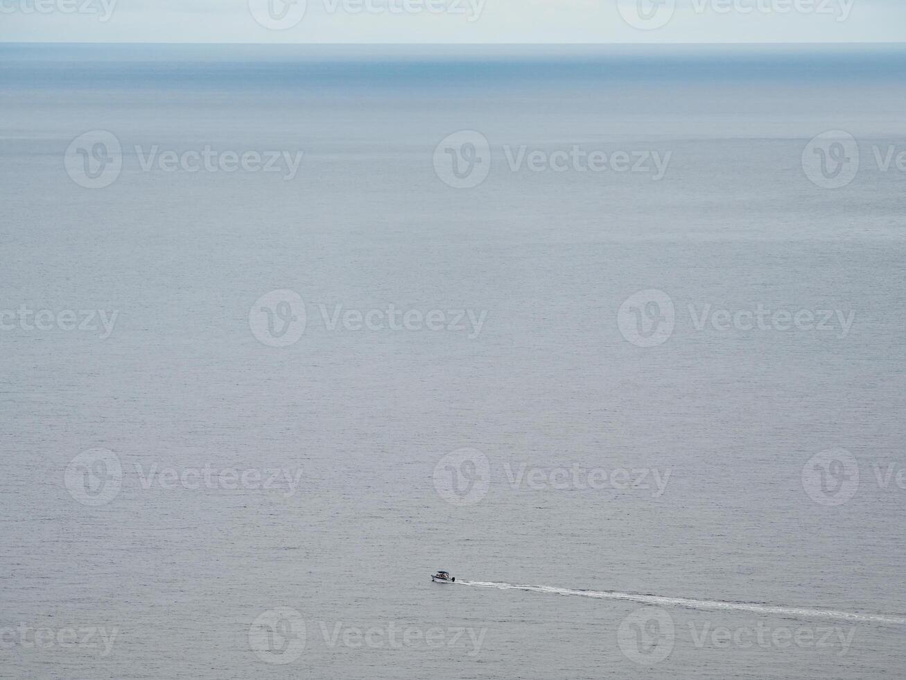 Small white boat sailing in the blue sea. photo
