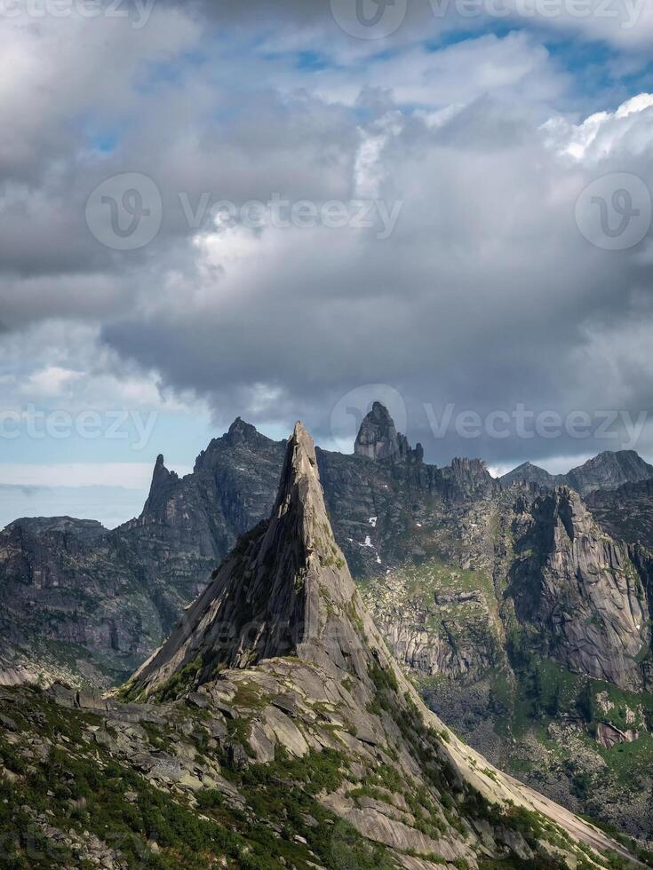 mountain silhouettes and large peaked top in rainy low stormy clouds photo
