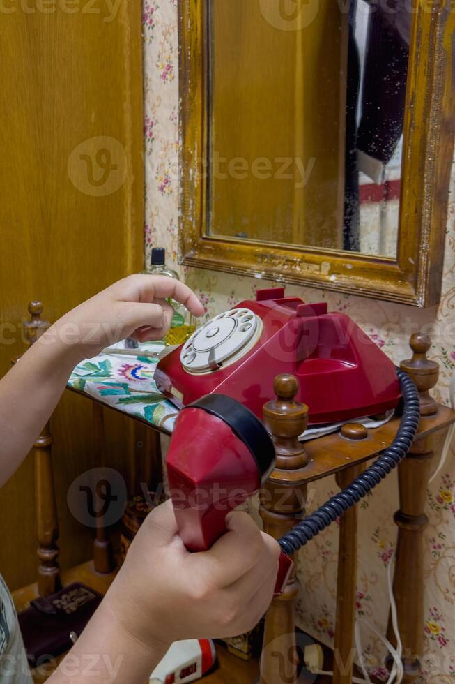 hand holds the receiver and calls from an old red phone photo