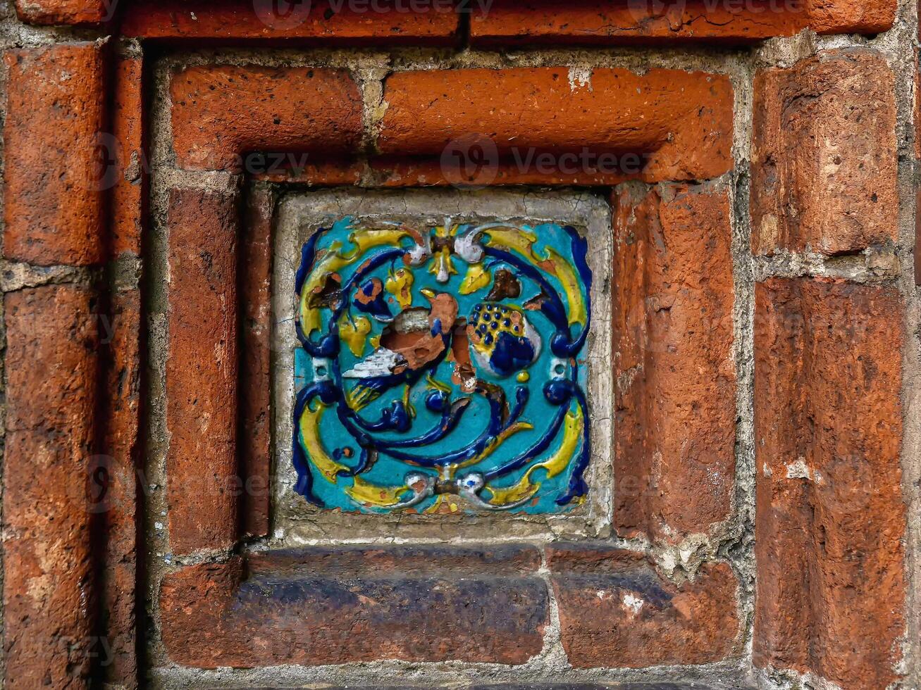 Ancient tiles in the red brick wall close up. Tile on exterior decor. photo