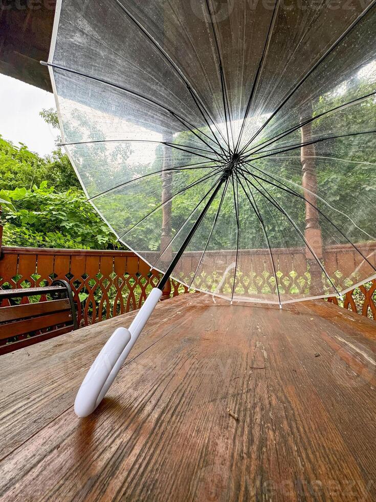 Forgotten umbrella on the wooden table of the veranda in the park. photo