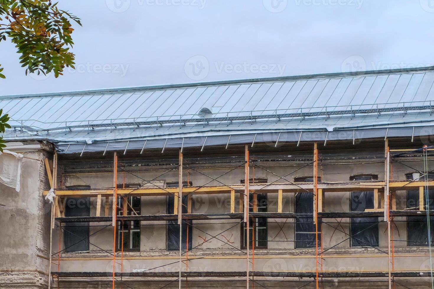 Repair of the roof of the building, galvanized iron sheets, wooden scaffolding at the facade of the building. photo