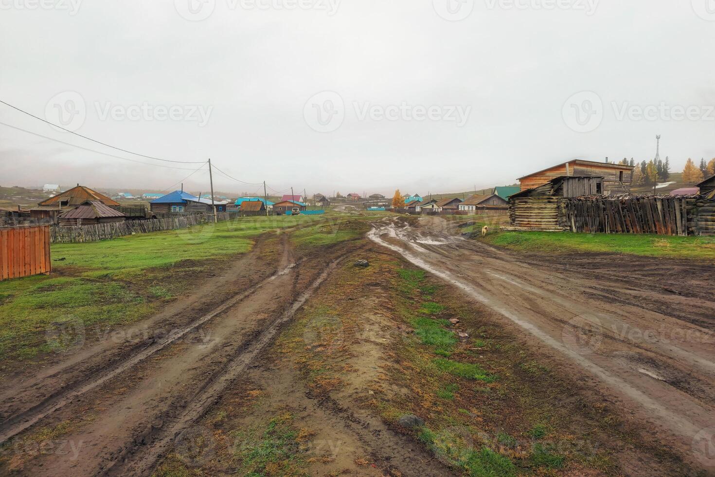 A rural road washed out by rains. Autumn dirt road, impassable mud through the village. Altai region. photo