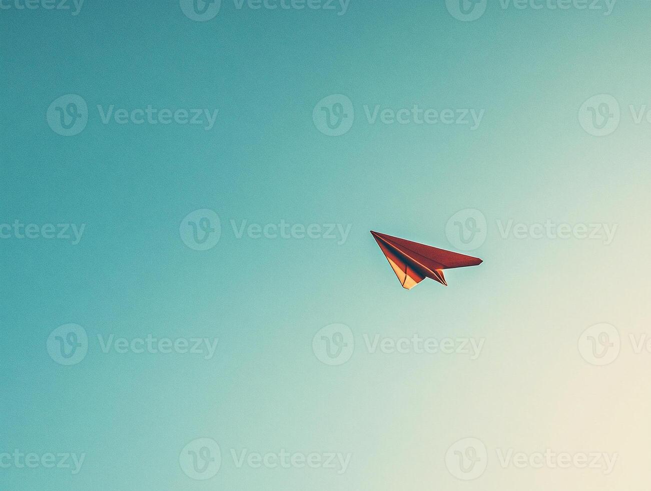 Minimalist red paper plane soaring in clear blue sky symbolizing freedom, ambition, and simplicity in a vibrant composition photo