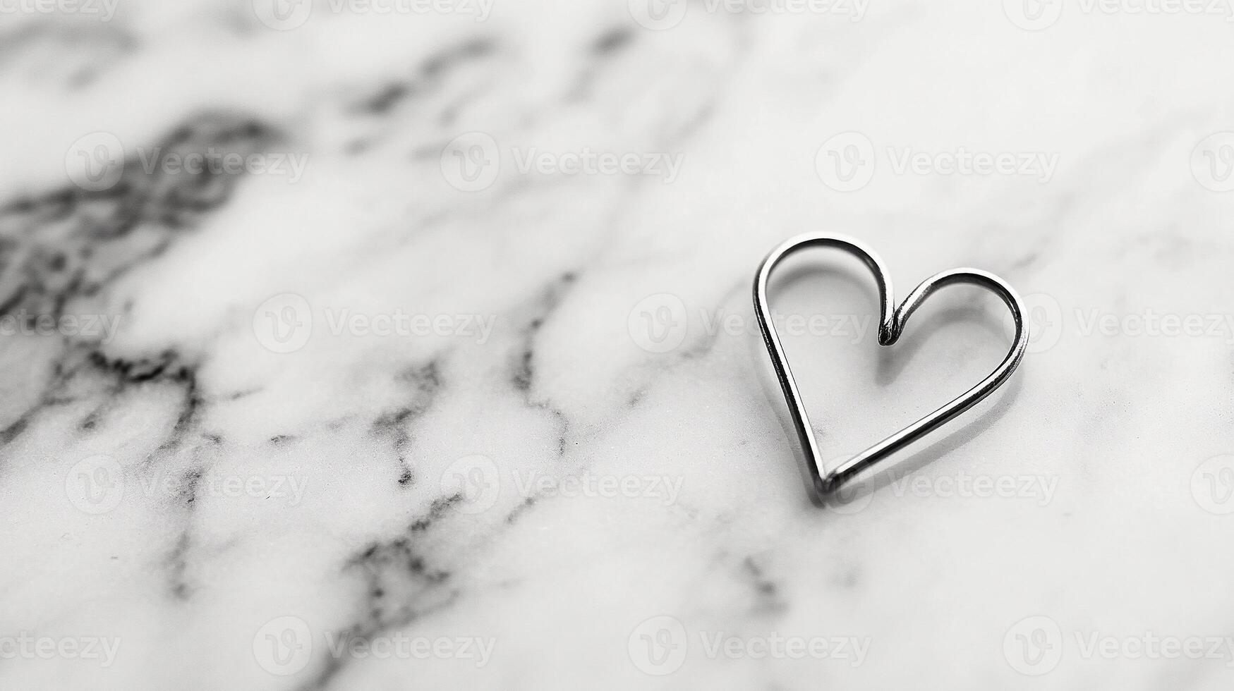 a Solitary paperclip bent into heart shape resting on white marble soft shadows and modern minimalist concept photo
