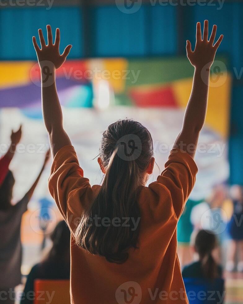 Back view of a child cheering enthusiastically at vibrant event with rainbow-colored lighting and energetic atmosphere photo