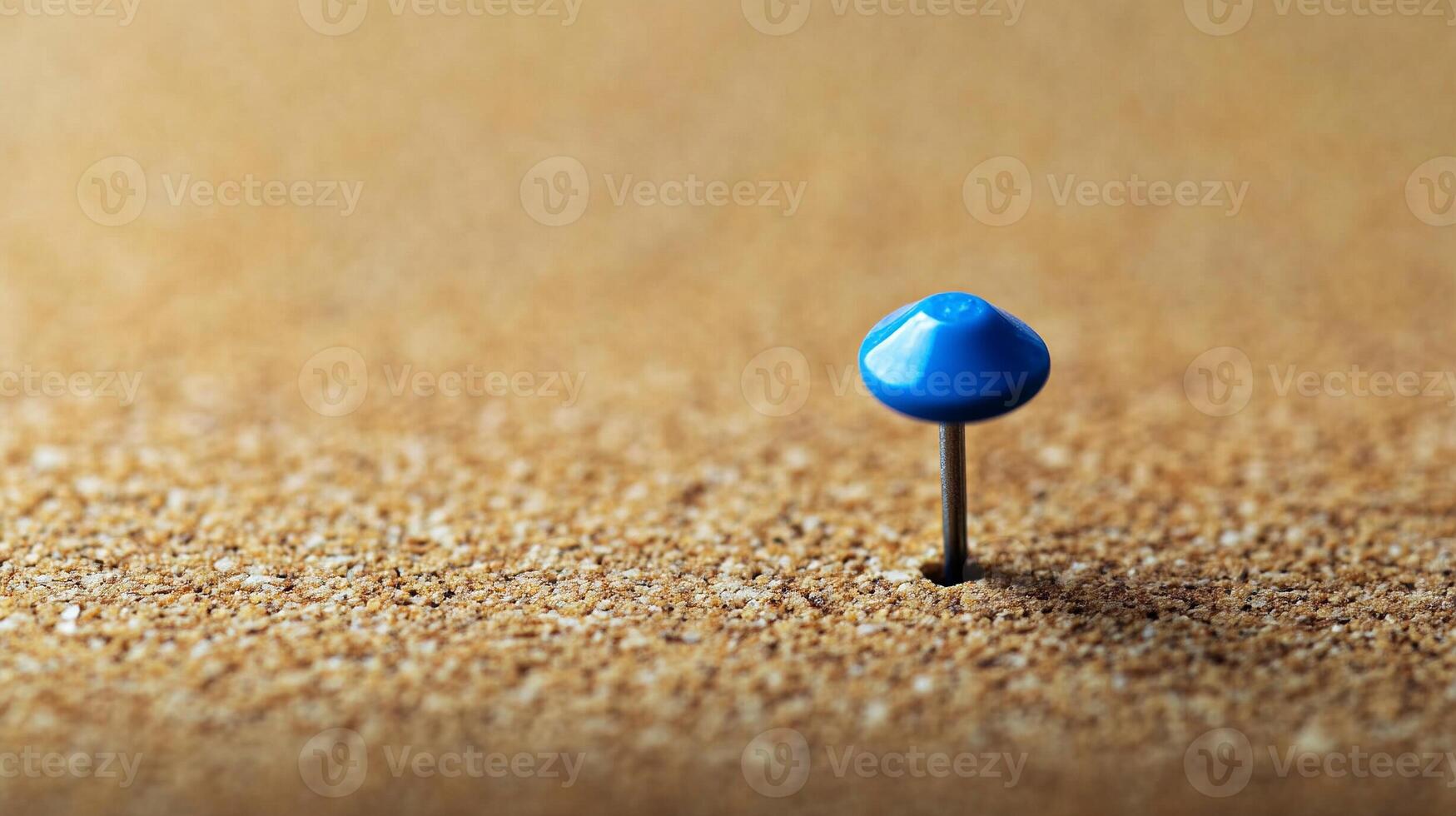 Single blue pushpin inserted into textured corkboard warm natural lighting photo