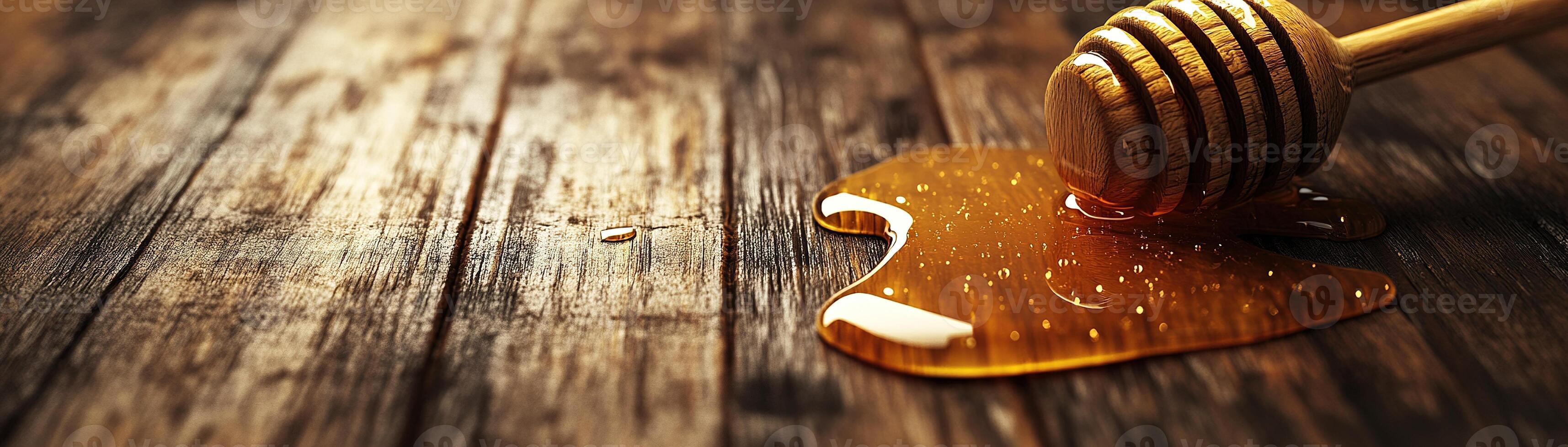 Golden honey glistens as it drips from a wooden dipper onto a smooth, weathered wooden surface. Soft natural light enhances the warm hues, creating an inviting atmosphere photo