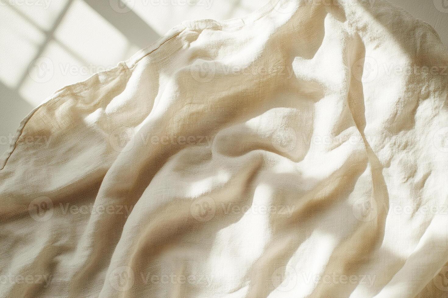 Crumpled beige linen fabric captures soft natural light and shadows, creating a tranquil and inviting ambiance, providing ample blank space for text overlay and design elements photo