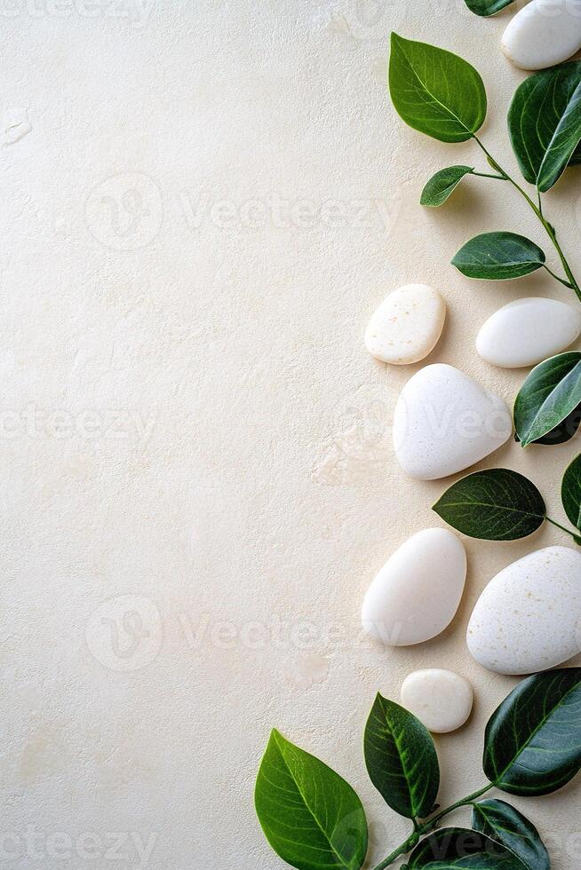 Smooth white and beige stones are arranged alongside lush green leaves on a matte beige surface, creating a serene and calming natural backdrop perfect for text overlay photo