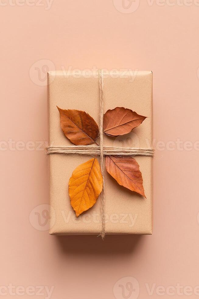 This unique gift box, made from recycled paper, features a charming decoration of dried autumn leaves and is tied with a thin cotton string, perfect for eco-conscious gifting photo
