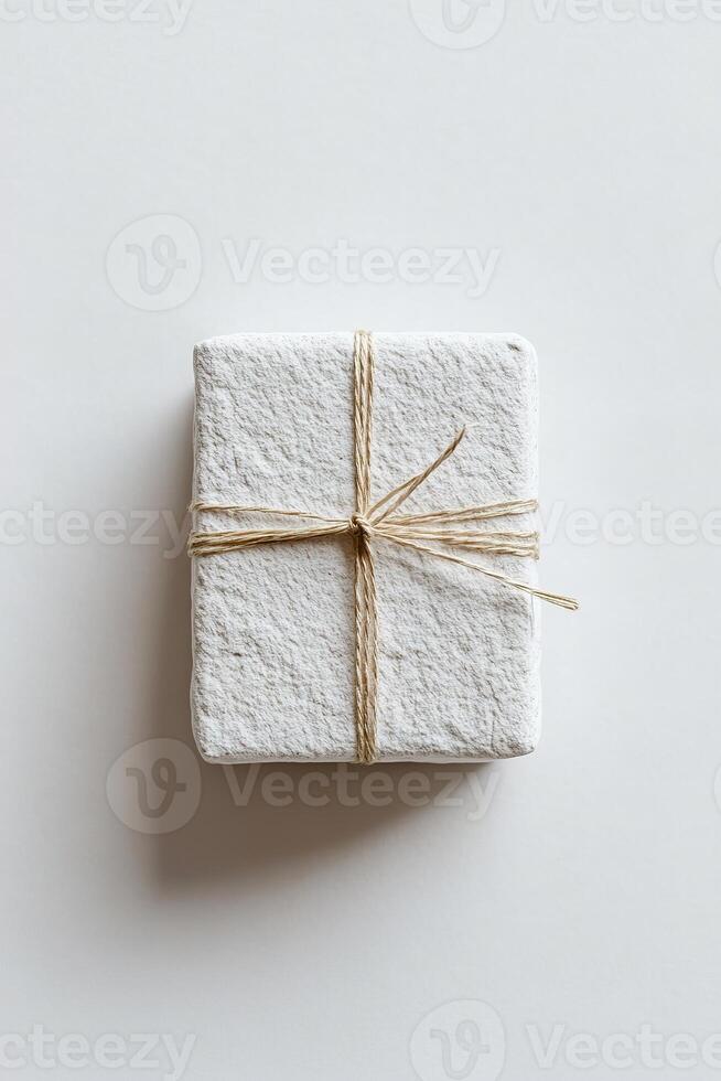 This elegant gift box features a soft stone texture in light gray, beautifully tied with a thin gold string, showcasing a modern, stylish design perfect for special occasions photo