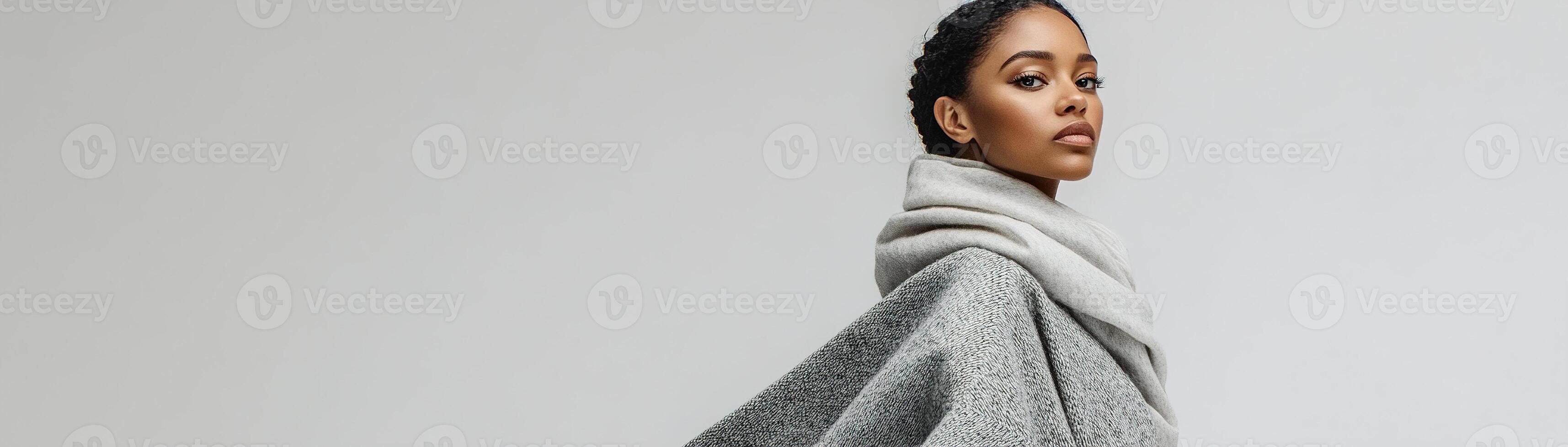 A model poses elegantly in a contemporary indoor studio, dressed in a chic gray blanket wrap and scarf, embodying winter fashion aesthetics photo