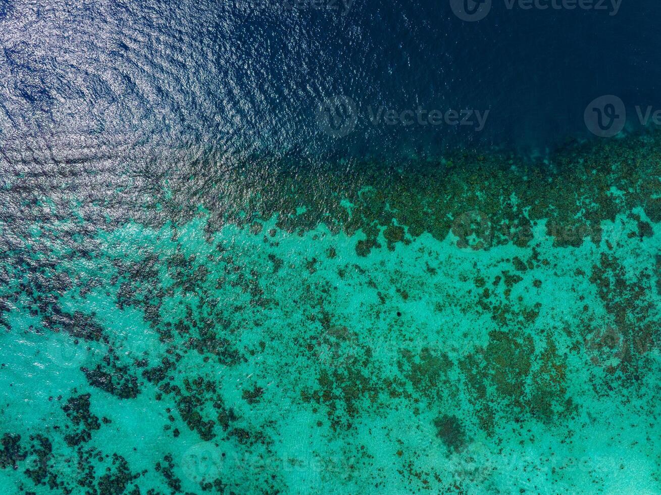 Aerial perspective of a vibrant coral reef near Phi Phi Islands, Thailand, with turquoise waters transitioning into deep blue ocean depths. photo
