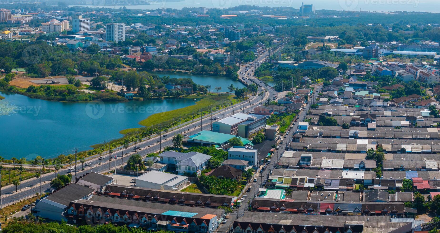 Aerial perspective of Phuket, Thailand, featuring a lotus pond, urban buildings, roads, greenery, and a distant coastline in the background. photo