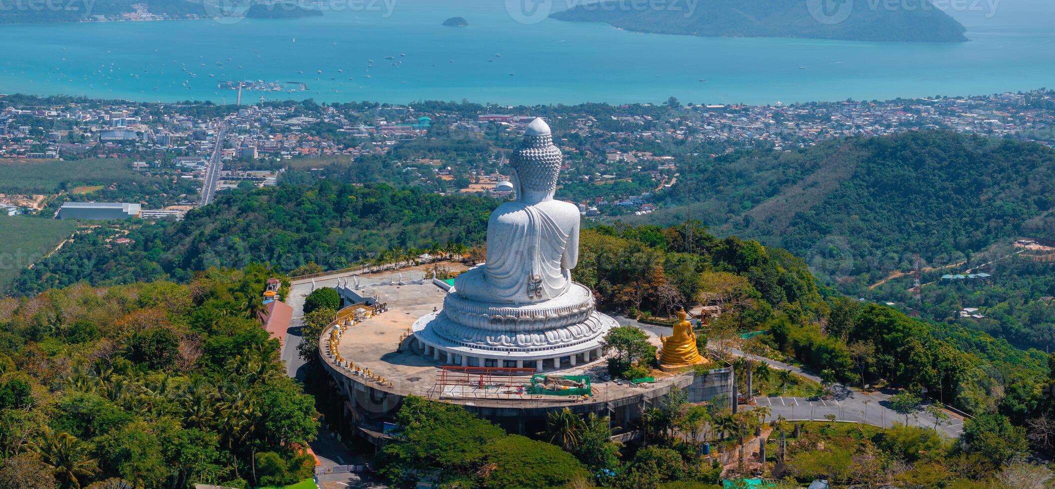 Aerial view of the Big Buddha statue on a hill in Phuket, Thailand, surrounded by greenery, with the Andaman Sea and islands visible in the background. photo