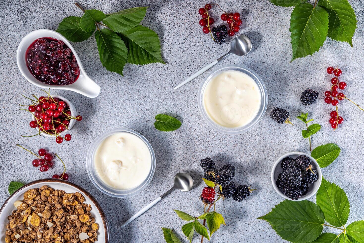 Yogurt, granola, blackberry, redcurrant and jam composing a healthy breakfast photo