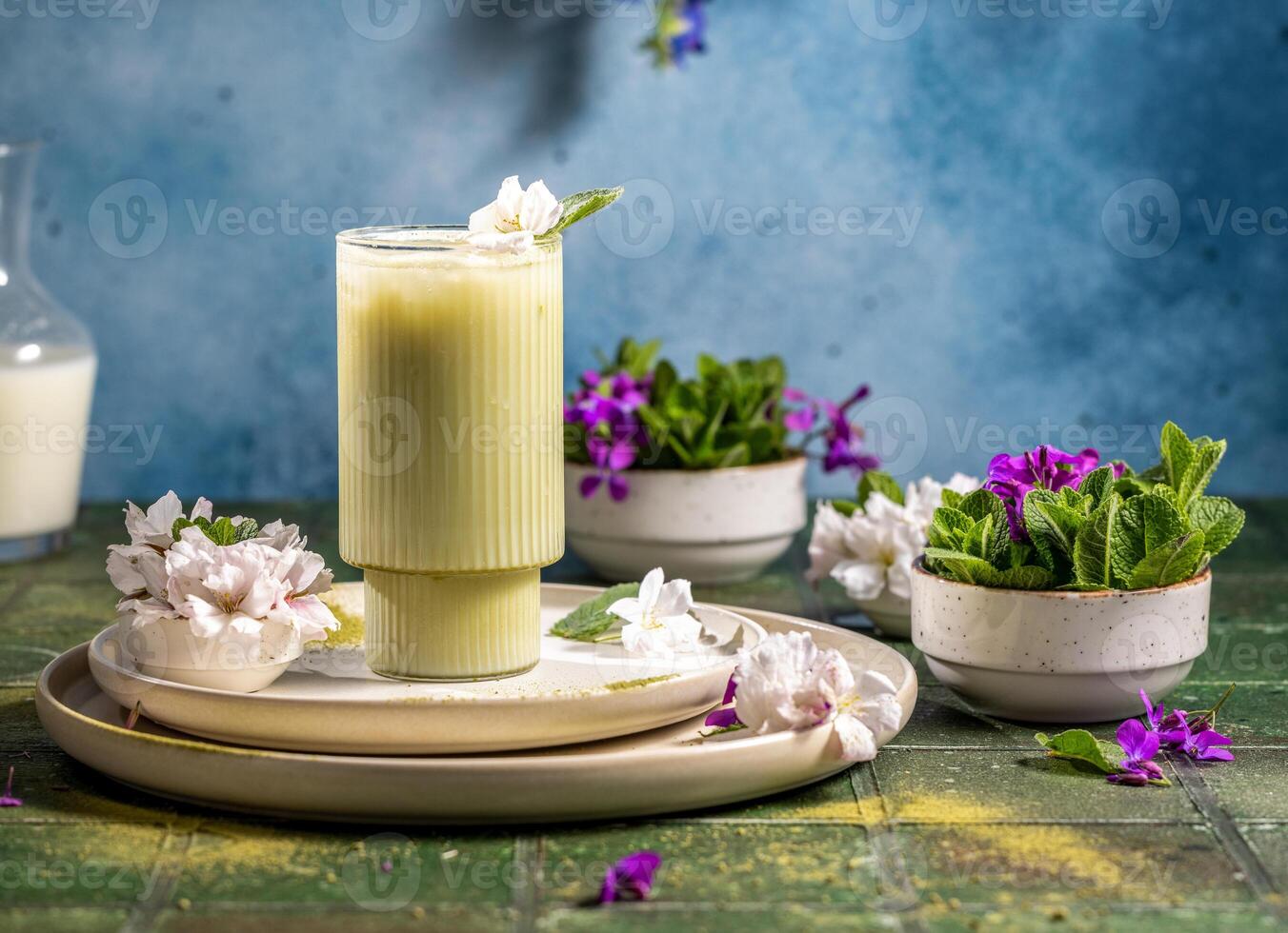 Iced matcha latte decorated with flowers and mint on green table photo
