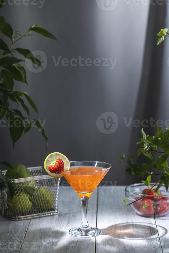 Refreshing strawberry cocktail garnished with lime and strawberry on wooden table photo