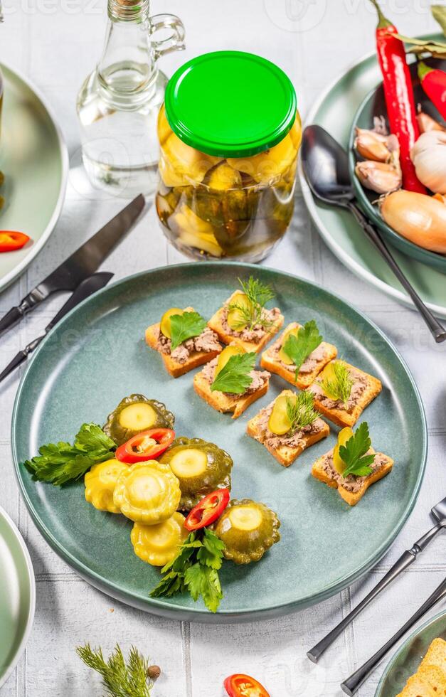 Pickled pattypan squash and canape with pate on festive table setting photo