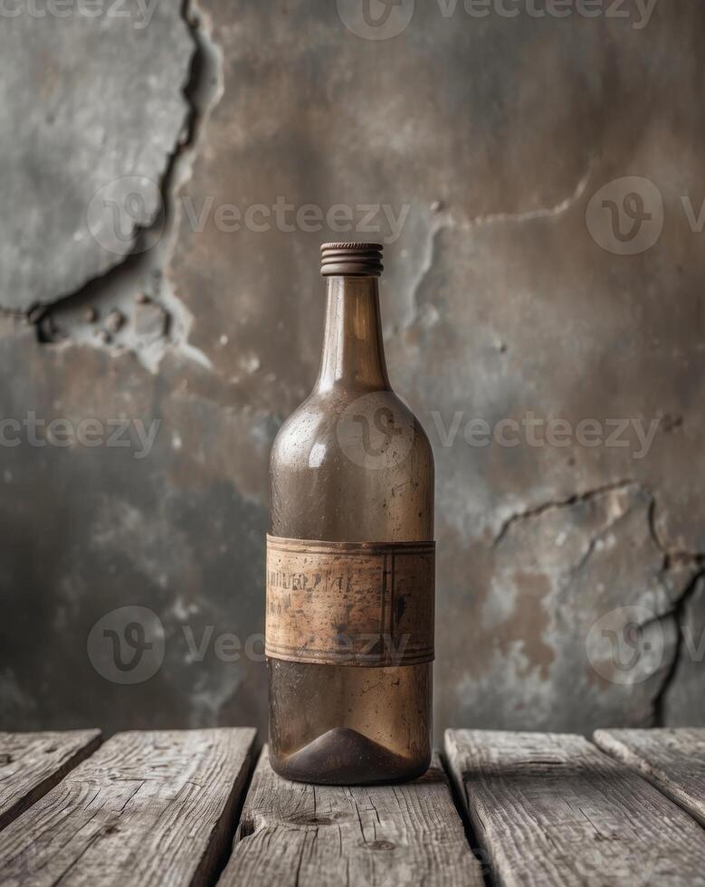 Old brown glass bottle is standing on a wooden surface with a grunge wall backgroundOld brown glass bottle is standing on a wooden surface with a grunge wall background. photo