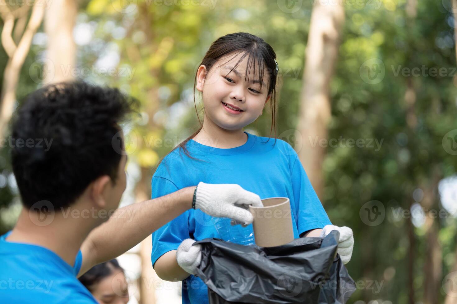 Child helping parent during a volunteer garbage collection event in the park photo