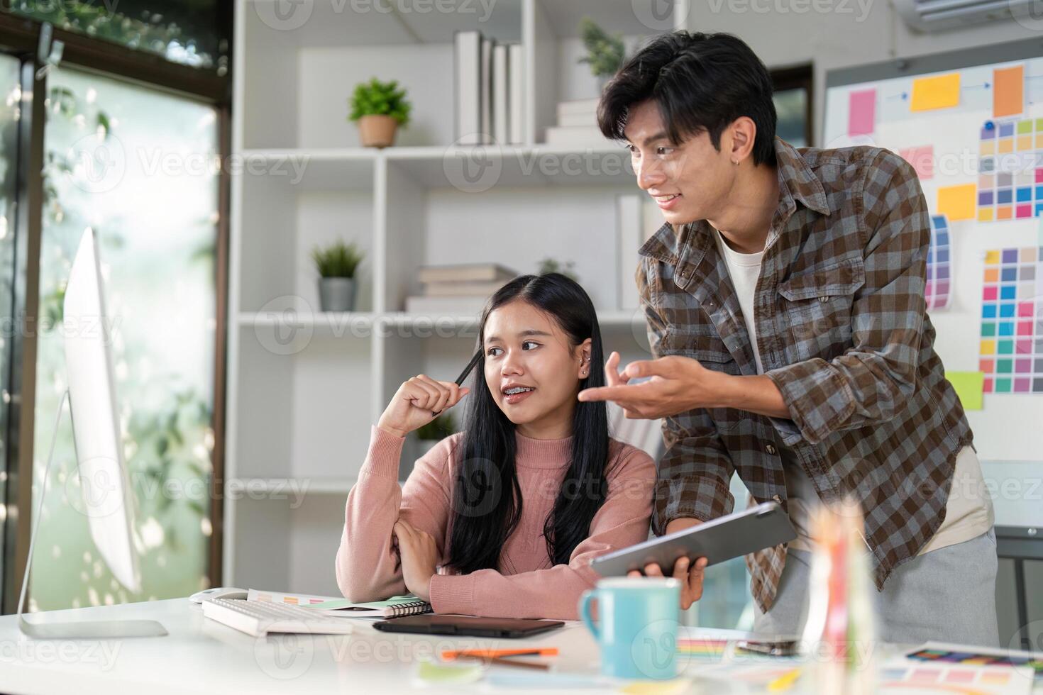 Design professionals engaging in a collaborative brainstorming session at a modern workspace, exploring graphics on a tablet photo